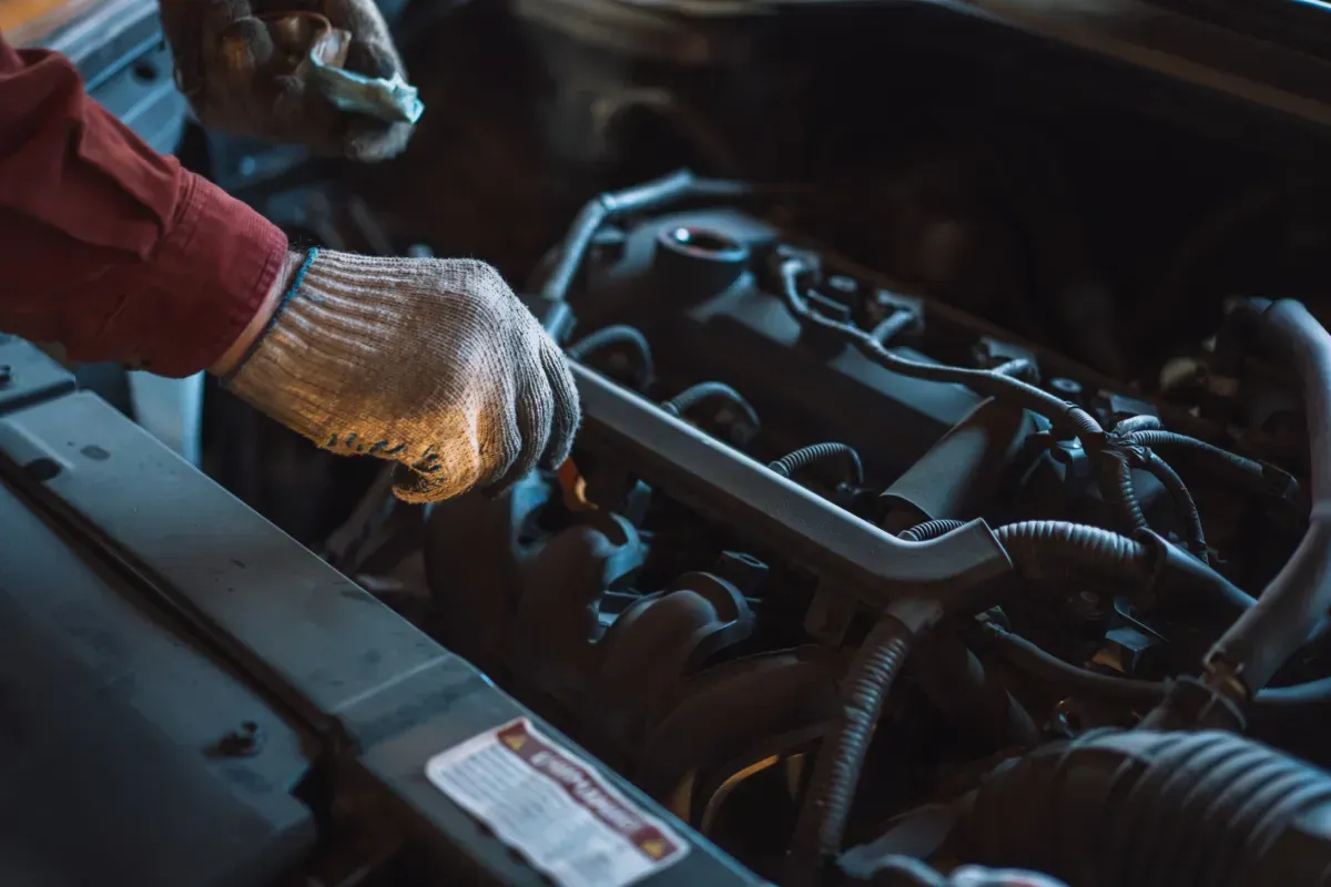 Mecánico con guantes utilizando una llave en el motor de un automóvil.