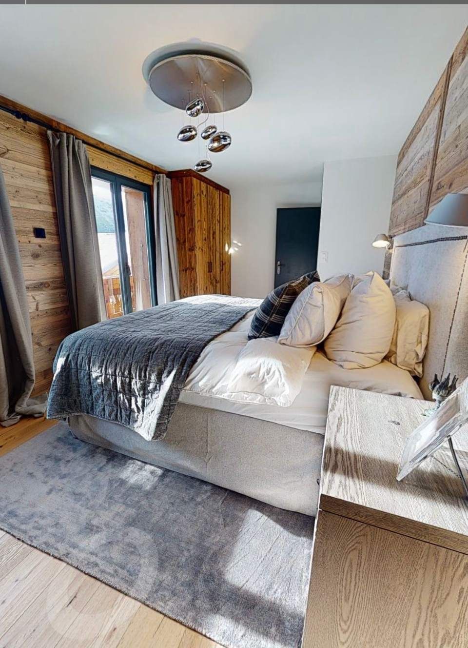 Chambre confortable avec un grand lit, des murs en bois et un tapis gris.