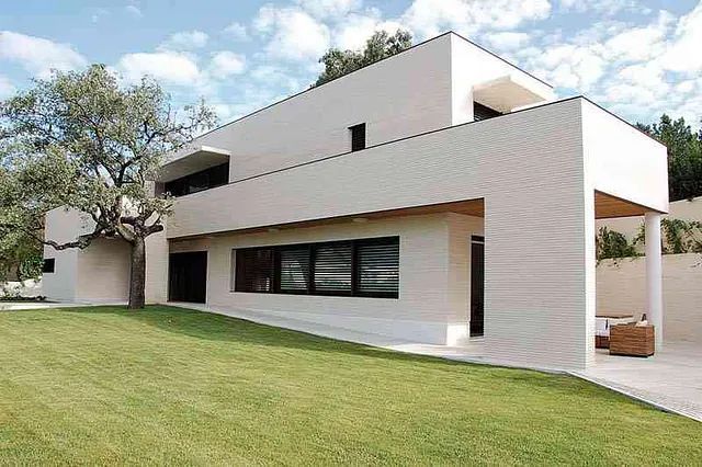 Una gran casa blanca con un exuberante césped verde frente a ella.