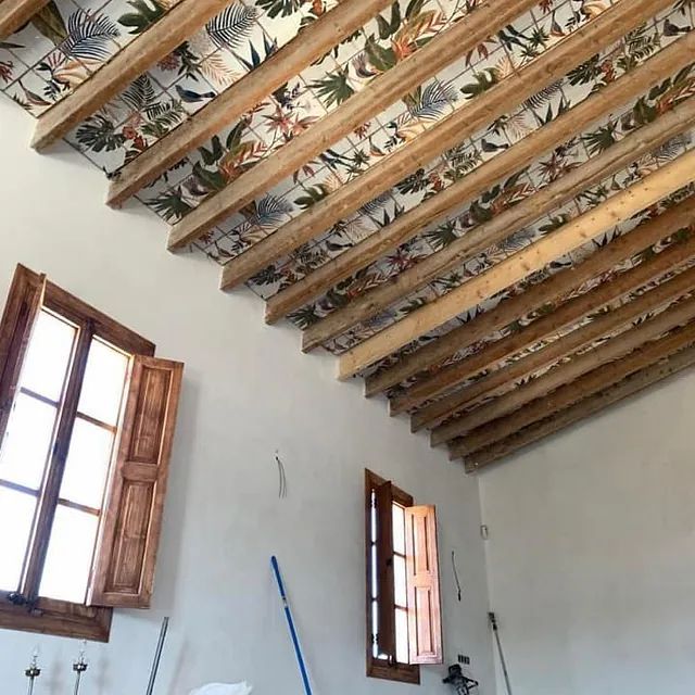 Una habitación con techo de madera y dos ventanas