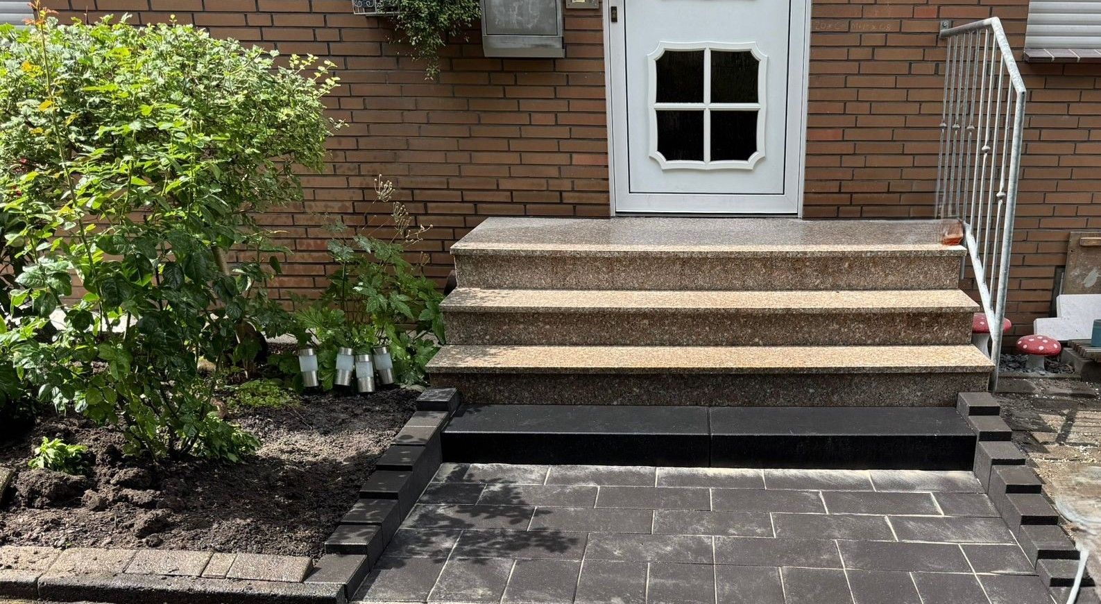 Eingangsbereich eines Wohnhauses mit Außentreppe aus Waschbeton-Stufen und dunkler Einfassung