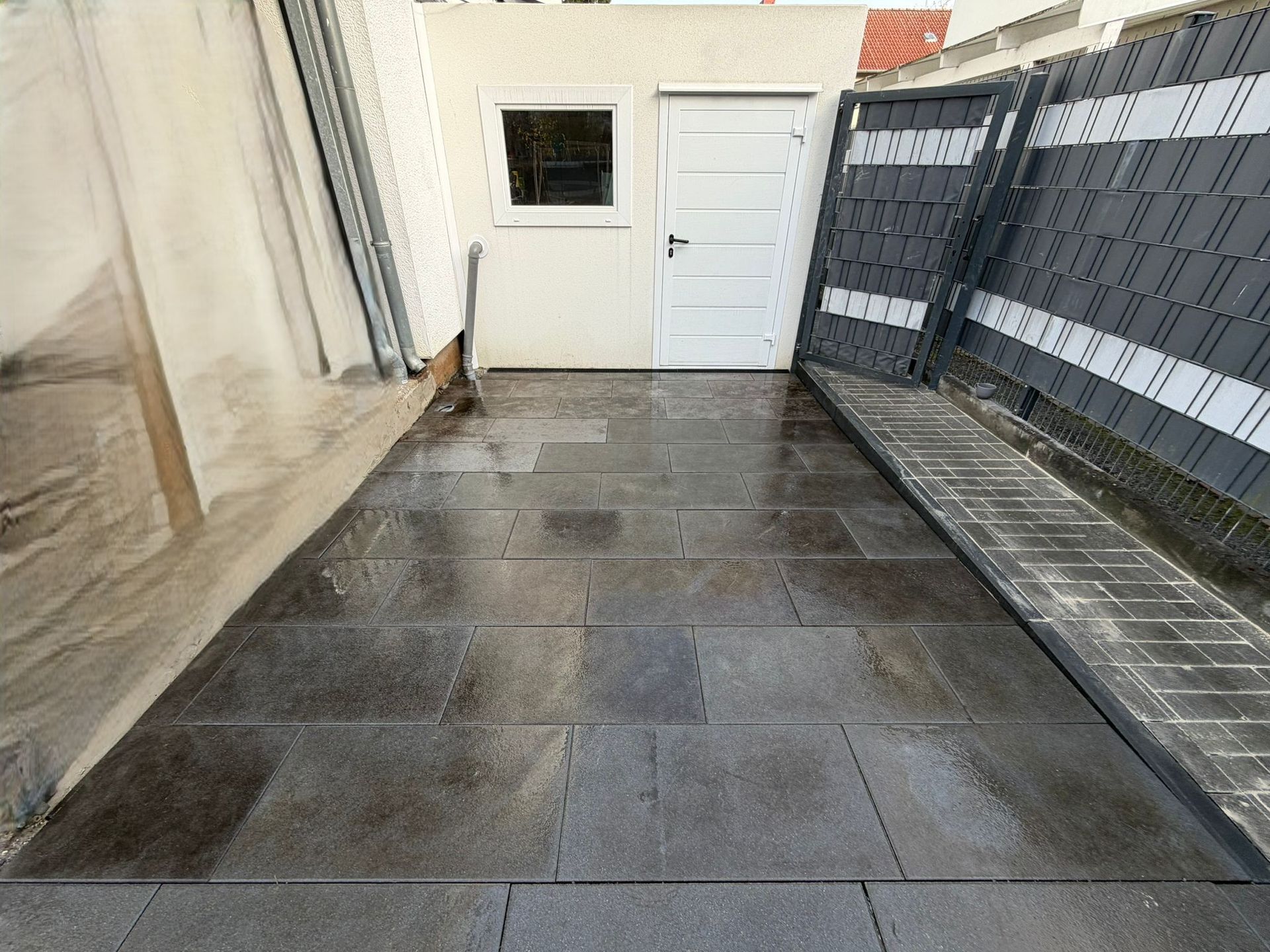 Frisch verlegter, dunkler Plattenbelag für eine Terrasse im Außenbereich mit hellen Fugen