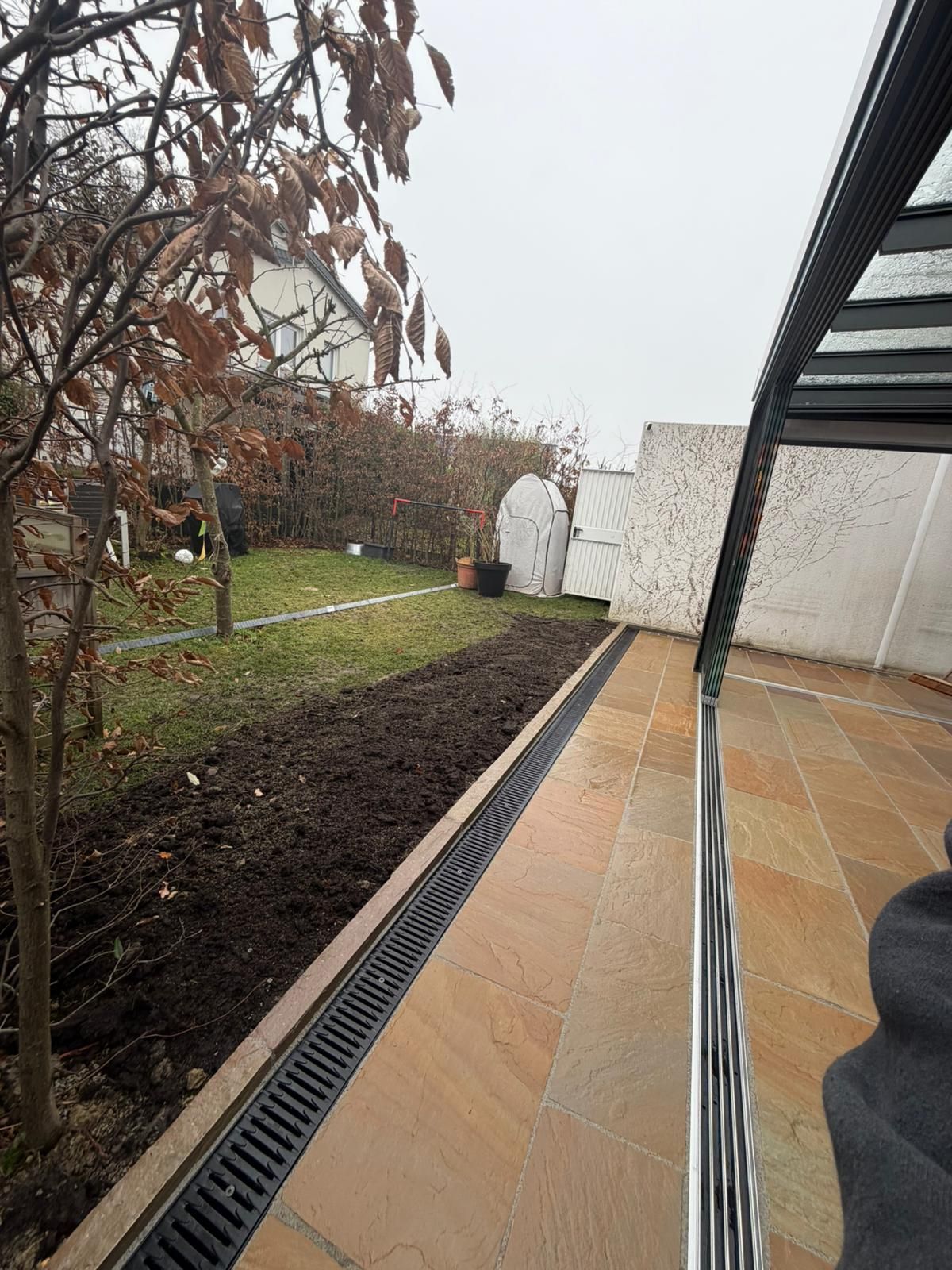 Aussicht von einer Dachterrasse oder einem Balkon mit anthrazitfarbenem Geländer auf ein herbstliches Grundstück.