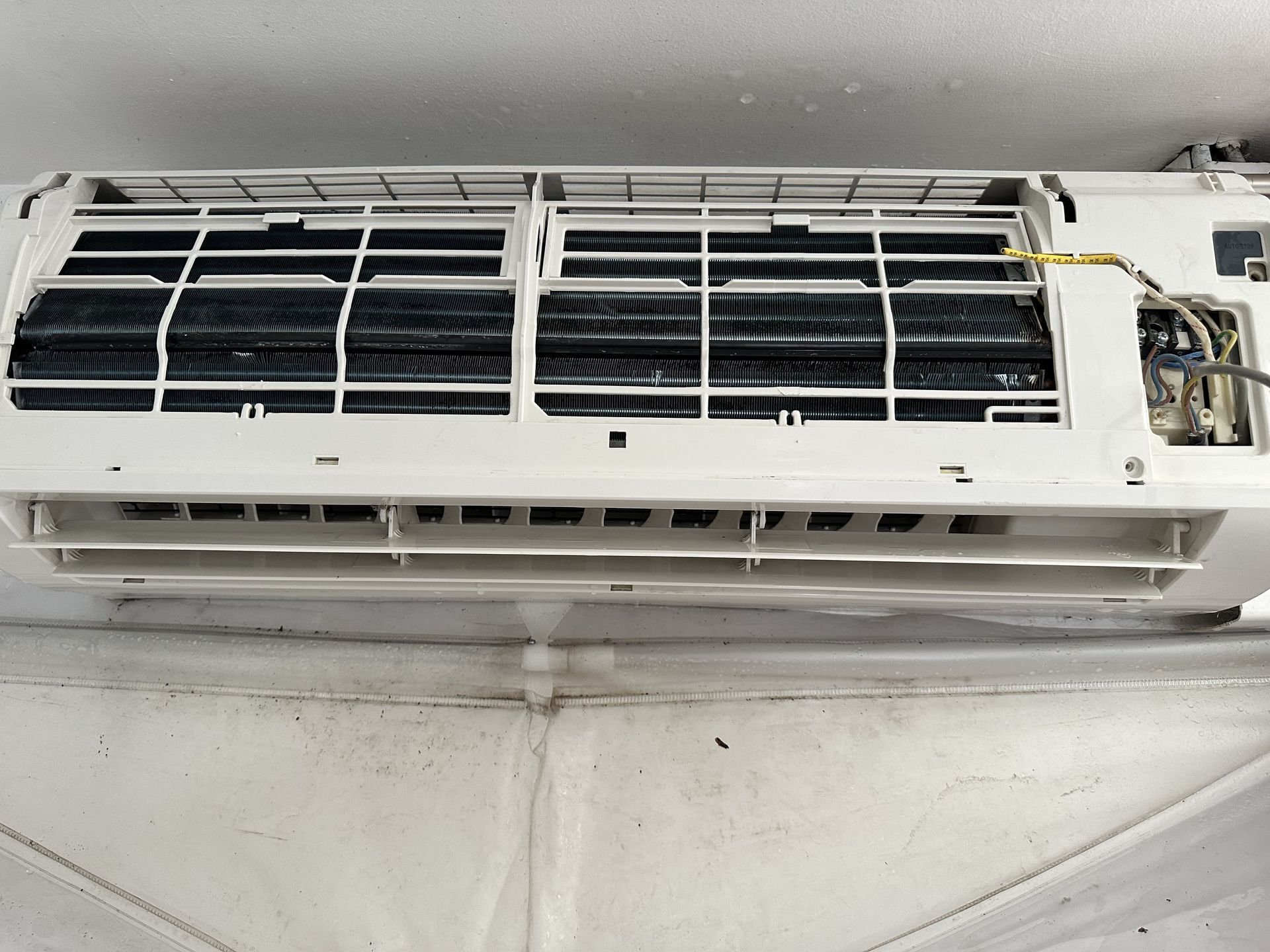 Un climatiseur blanc est posé sur un mur blanc.