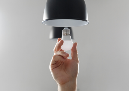 Une personne tient une ampoule à la main sous une lampe.