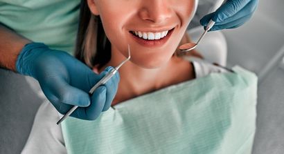 Criança no dentista; boca aberta, sendo examinada com espelho e instrumentos. Quarto escuro, close-up.