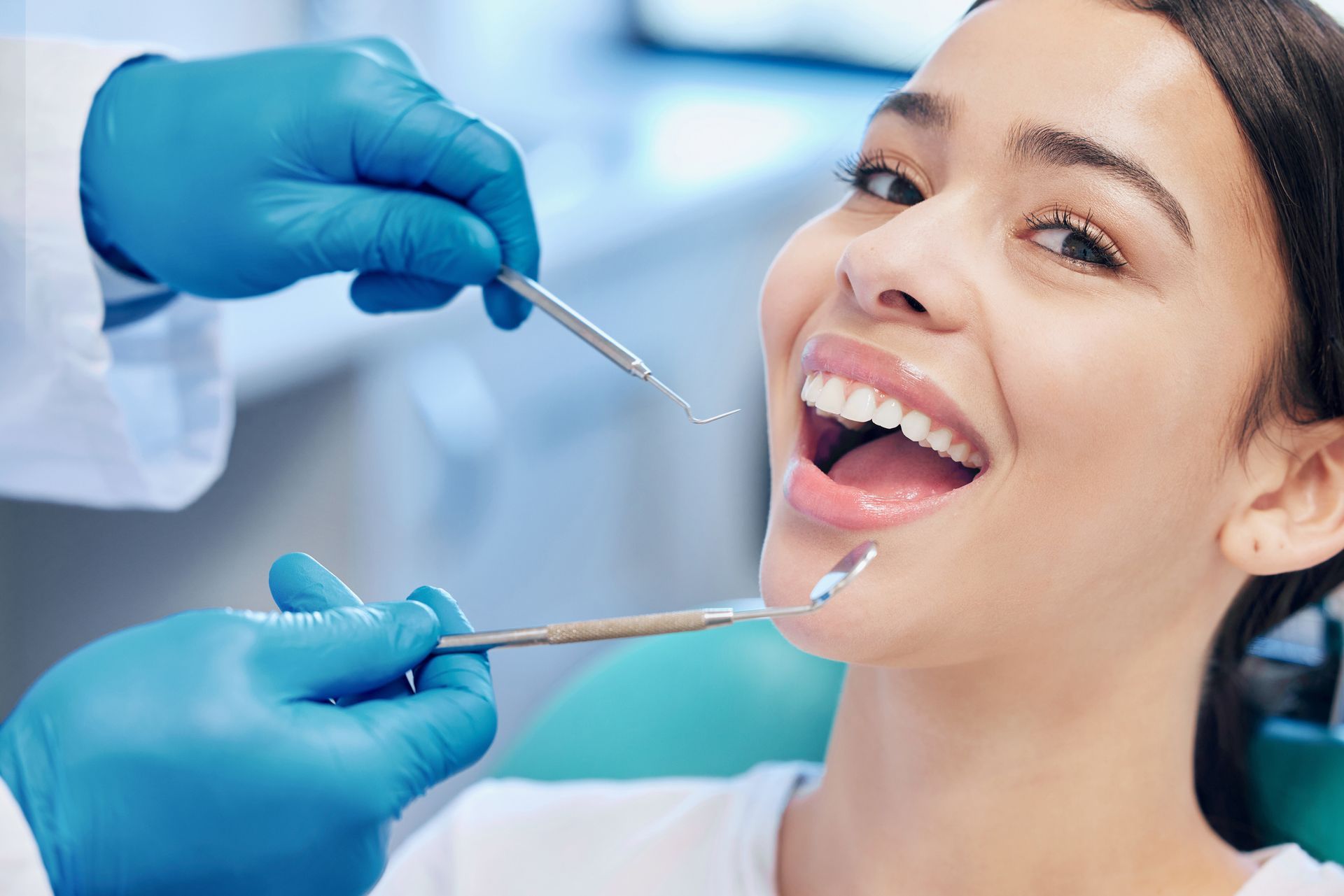 Dentista examinando a boca de um paciente sorridente em um consultório odontológico.