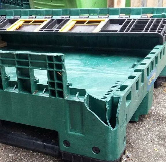 Una caja de plástico verde con una tapa amarilla se encuentra en el suelo.