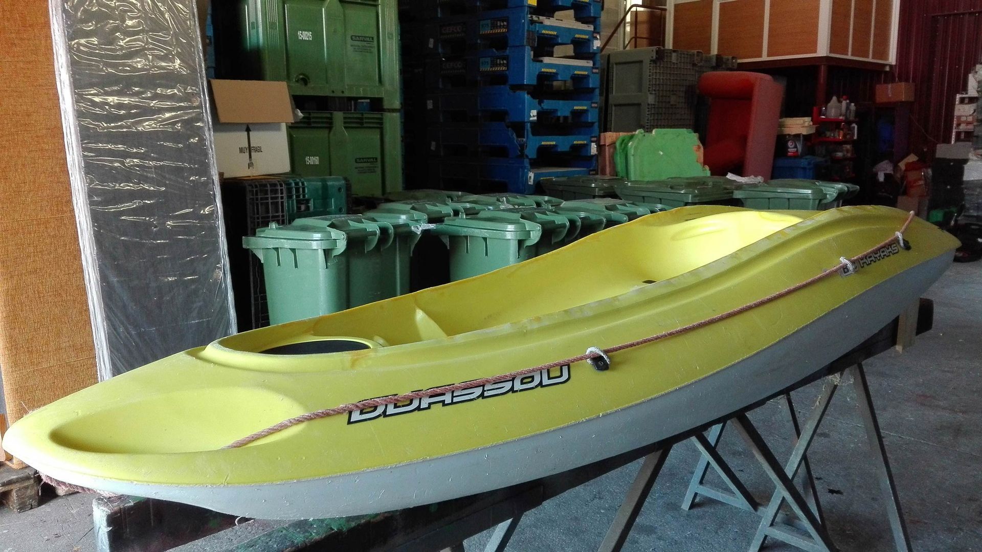Un kayak amarillo está sobre una mesa en un almacén.