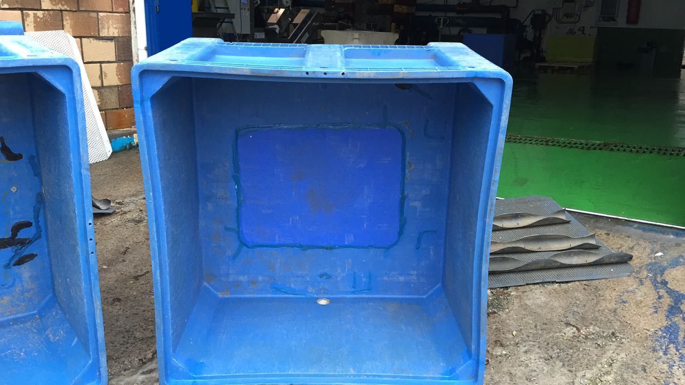 Hay dos cajas de plástico azules una al lado de la otra en el suelo.