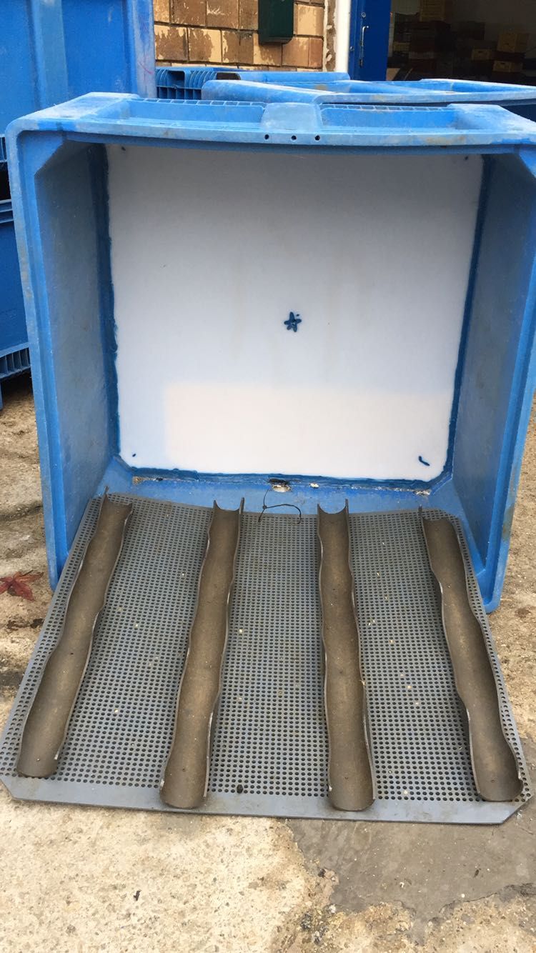 Un recipiente de plástico azul con una tapa blanca está colocado encima de una estera de metal.