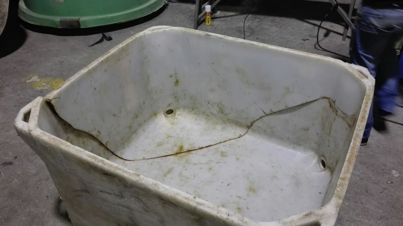 Un contenedor de plástico blanco sucio está en el suelo.