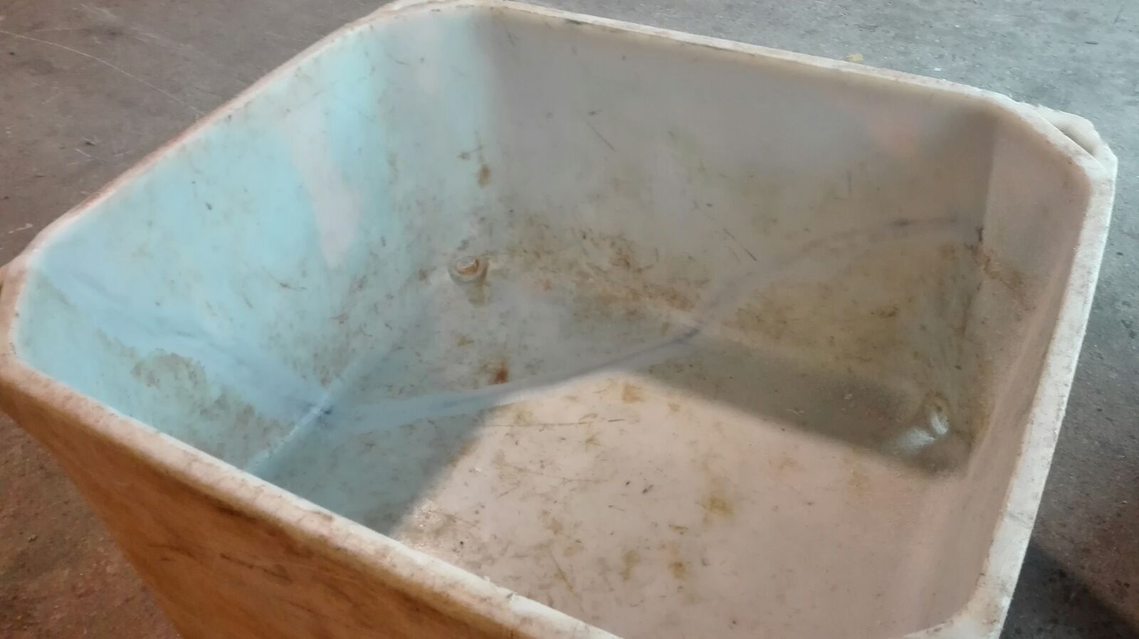 Un contenedor de plástico blanco sucio está en el suelo.