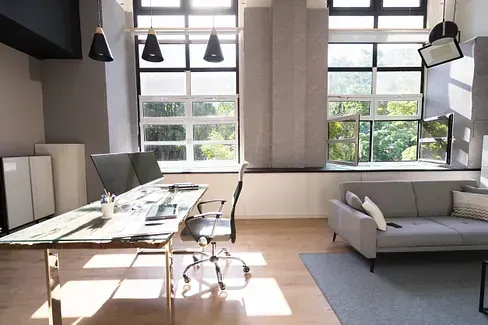Una sala de estar con sofá, escritorio, silla y computadora.