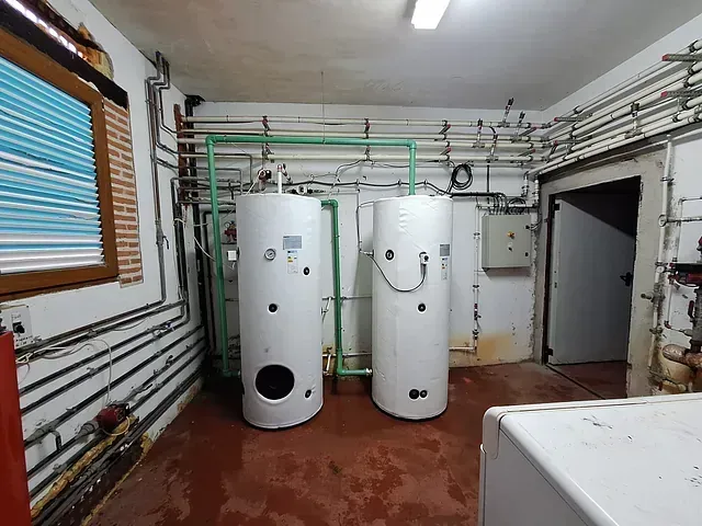 Dos calentadores de agua están en una habitación con tuberías.