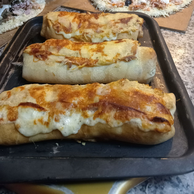 Trois burritos grillés sur une plaque de cuisson noire, légèrement dorés.