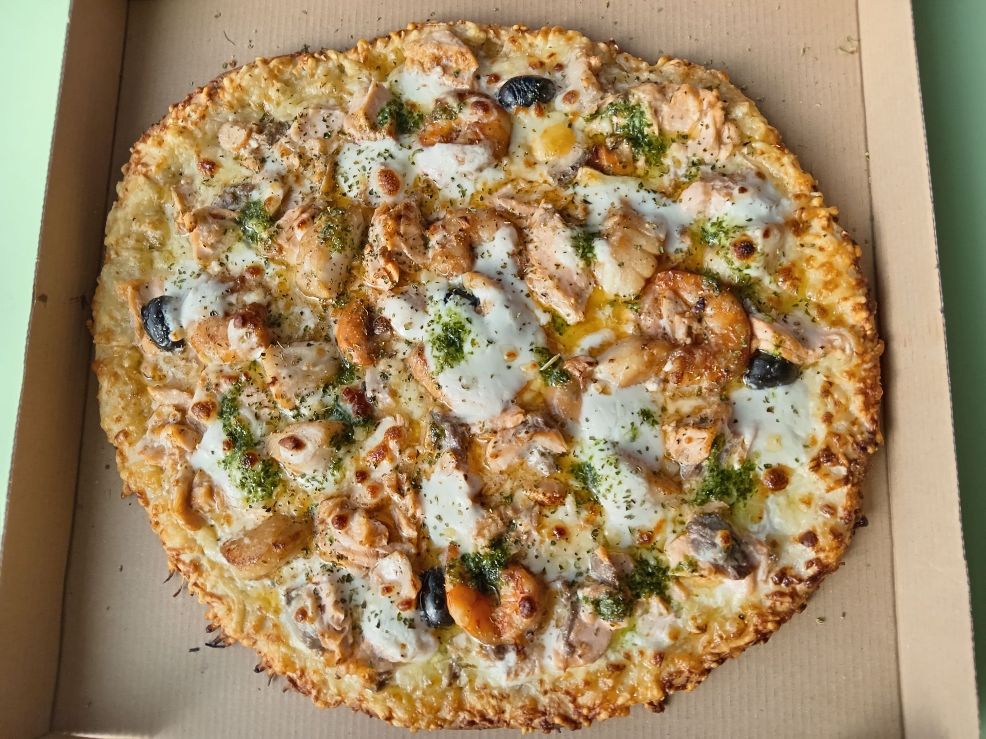 Pizza au fromage avec olives noires et herbes dans une boîte en carton ouverte