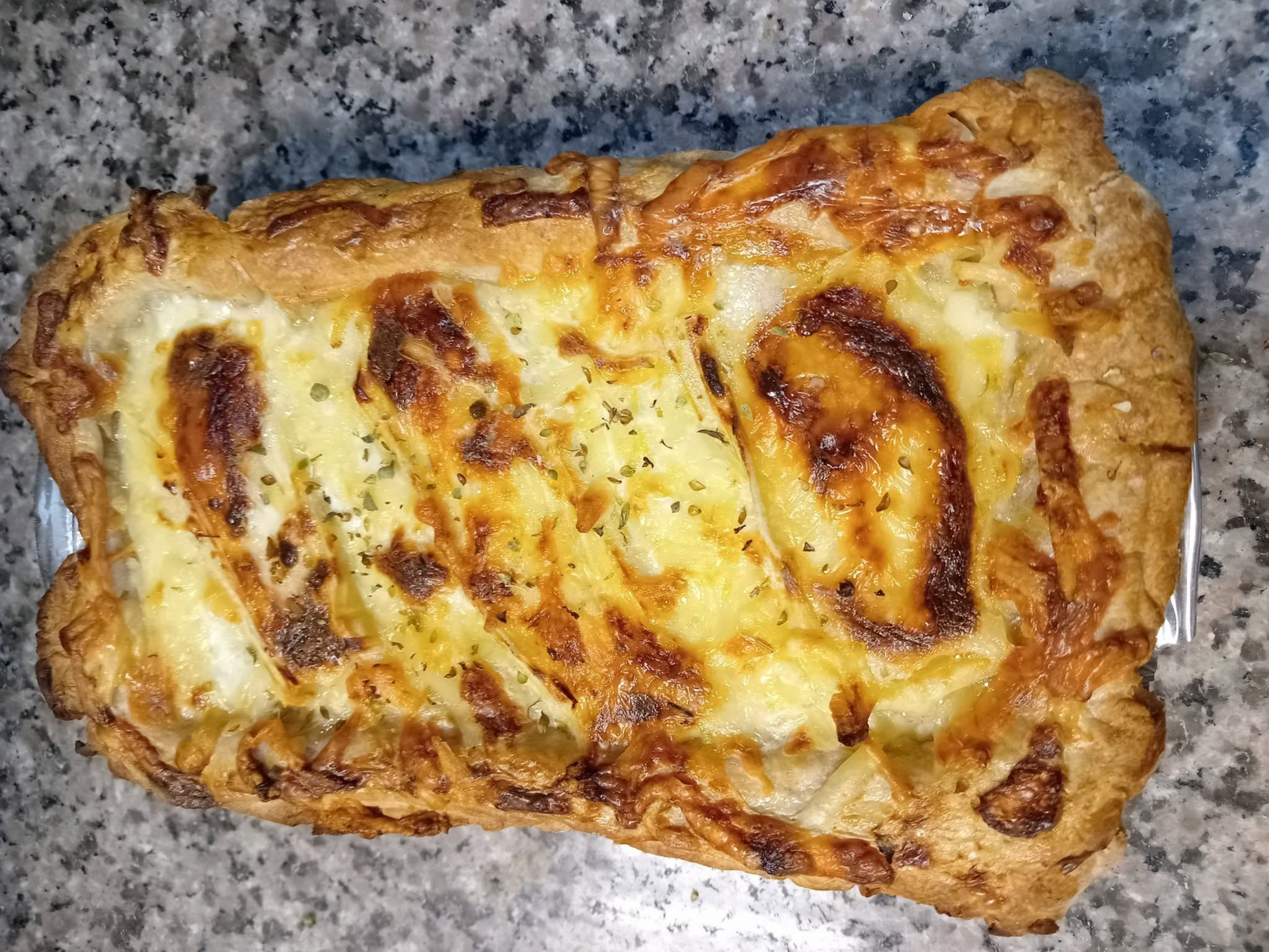 Pain plat garni de saumon fumé, de fromage à la crème, d'herbes et de quartiers de citron, posé sur un comptoir de cuisine.