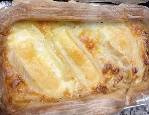 Gratin de fromage cuit au four dans un plat recouvert de papier aluminium, avec une surface dorée.