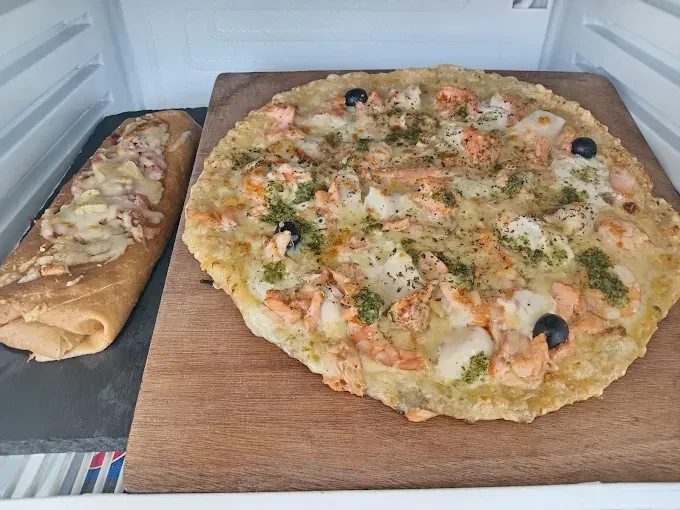 Une pizza et un pain à l'ail sur des planches en bois dans un réfrigérateur