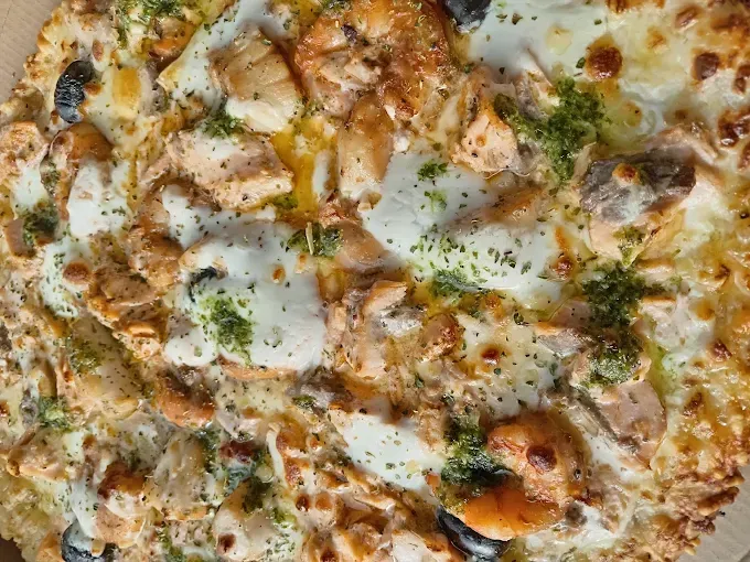 Gros plan sur une pizza au fromage garnie d'herbes et de morceaux de croûte dorée