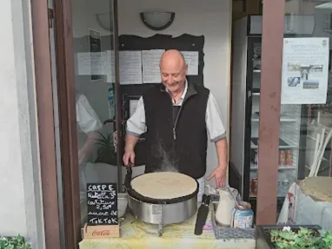Un homme sert un grand plat rond ressemblant à un gâteau sur un étal de marché.