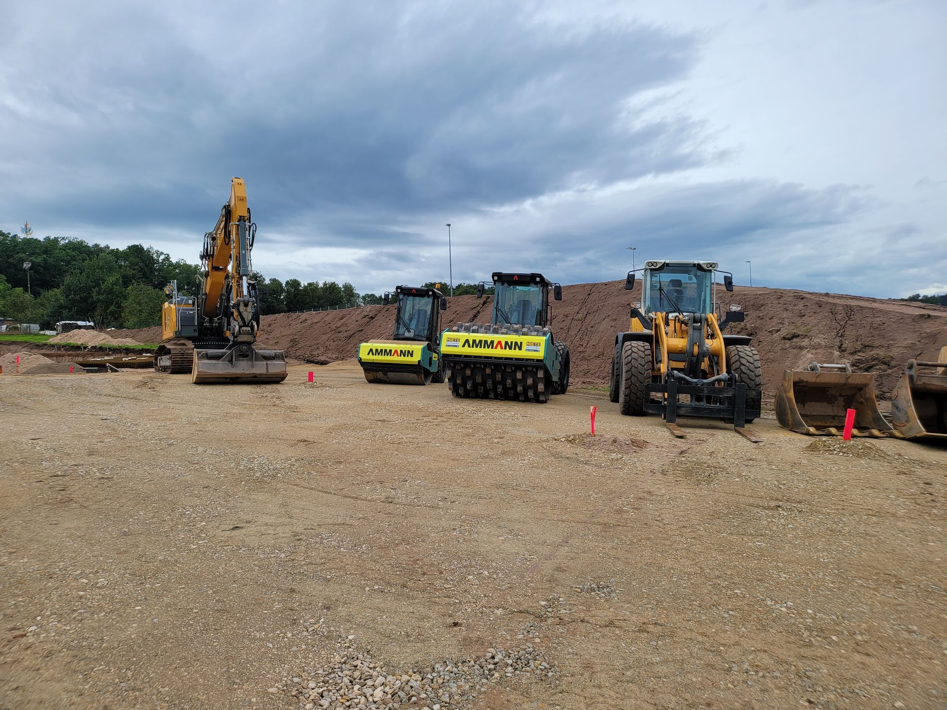 Zwei gelbe Bagger und ein Bulldozer, die auf einer Baustelle