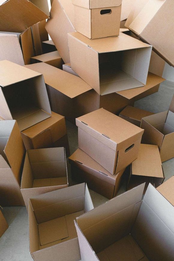 Pila de cajas de cartón marrón, algunas abiertas, en el suelo.