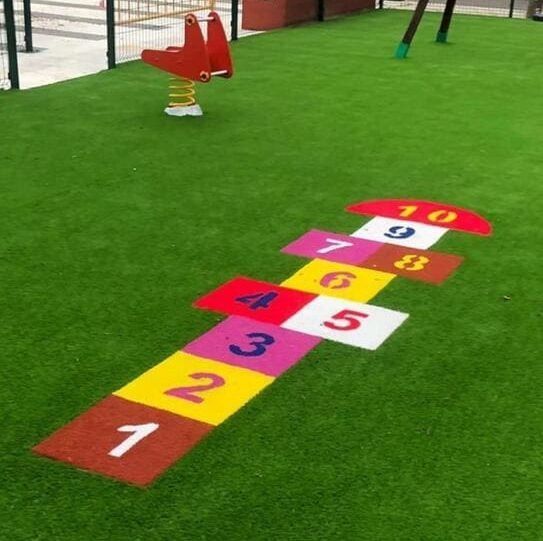 Un juego de rayuela está pintado en el césped de un patio de recreo.