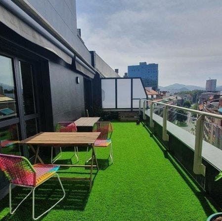 Un balcón con una mesa y sillas encima de un exuberante césped verde.