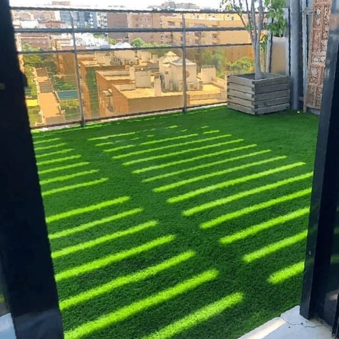 Un balcón con mucho césped verde y sombras.