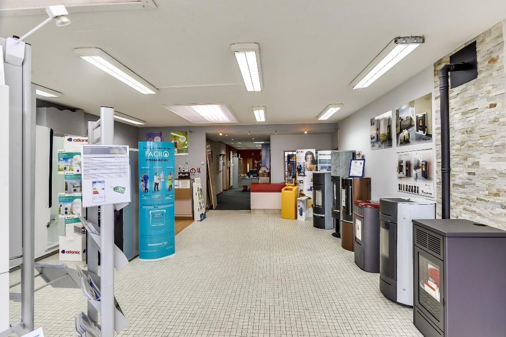 Hall d'entrée lumineux avec présentoirs, étagères et distributeurs automatiques le long d'un couloir carrelé.