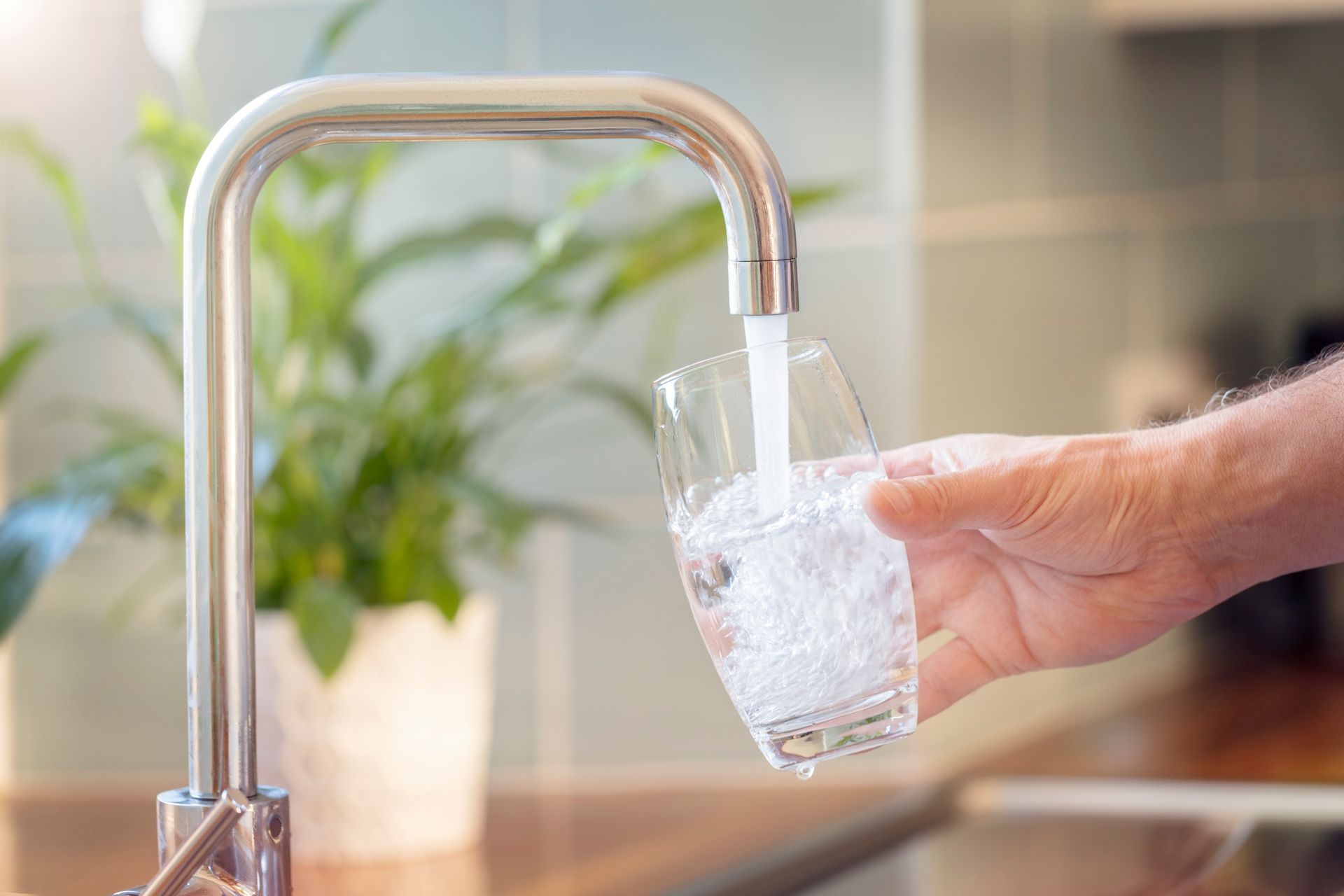 Remplissage manuel d'un verre transparent avec de l'eau provenant d'un robinet de cuisine.