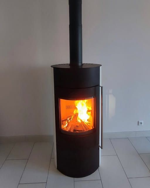 Poêle à bois noir avec un feu vif qui brûle dans une pièce carrelée.
