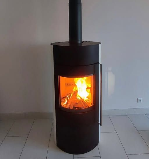 Poêle à bois noir avec un feu allumé dans une pièce carrelée.