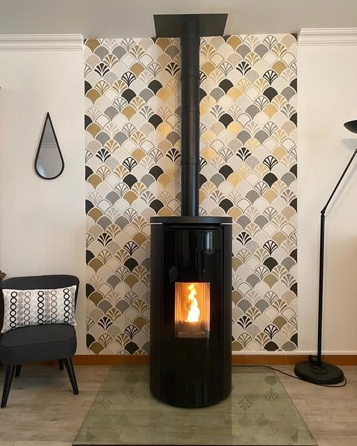 Salon moderne avec poêle à bois noir, papier peint à motifs, fauteuil et lampadaire.