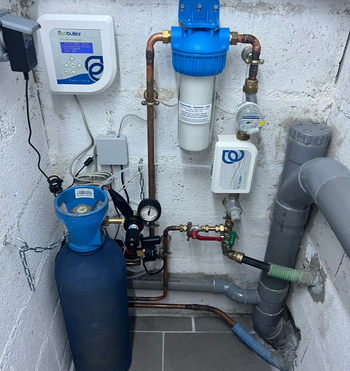 Système de filtration d'eau extérieur avec réservoir bleu, tuyaux, manomètres et boîtiers de commande muraux.