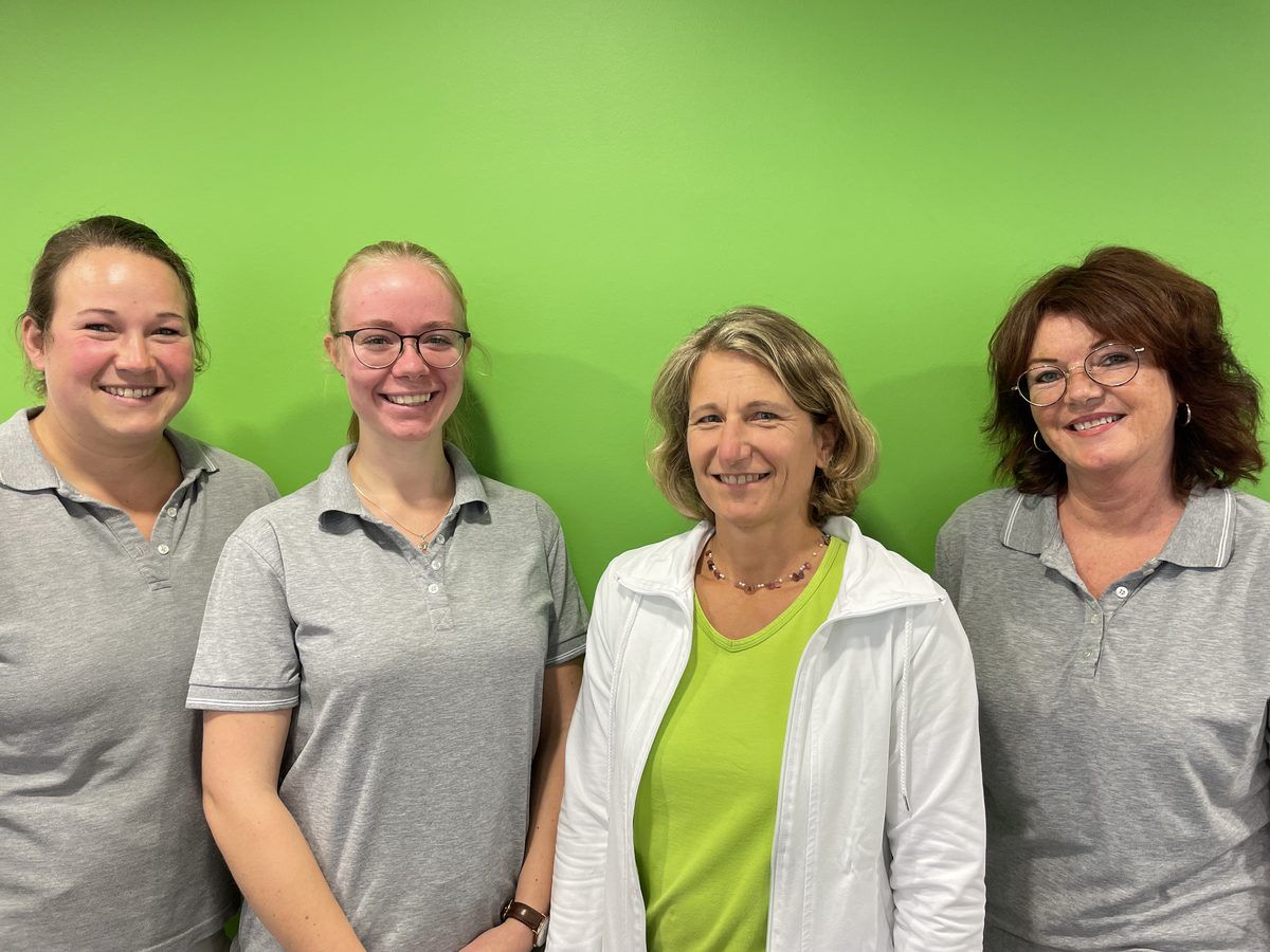 Vier Frauen posieren für ein Foto vor einer grünen Wand.