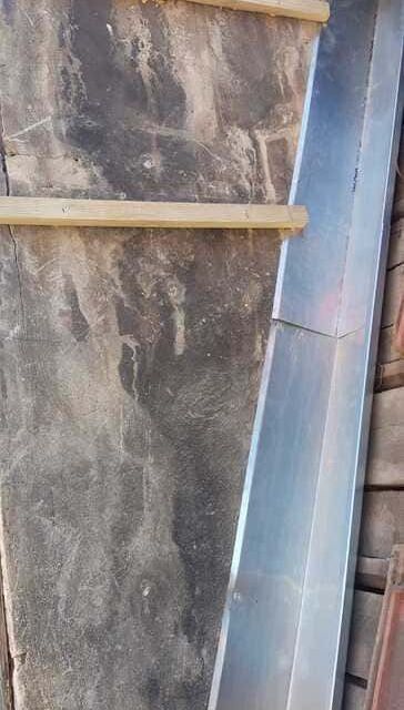 Revestimiento metálico instalado a lo largo de la superficie de un tejado de madera deteriorado por la intemperie.