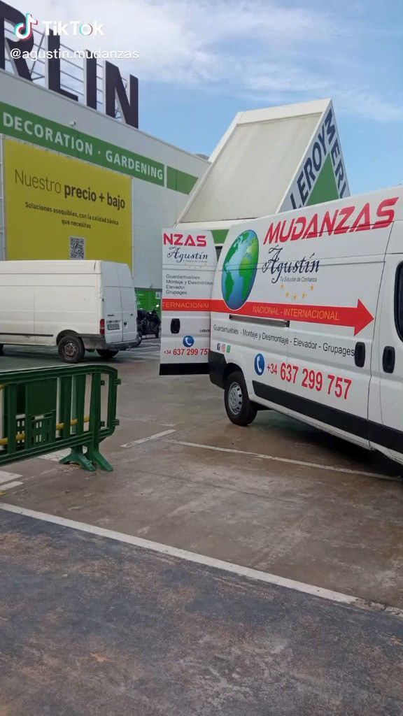 Camiones de mudanza blancos estacionados frente a un edificio con la etiqueta 