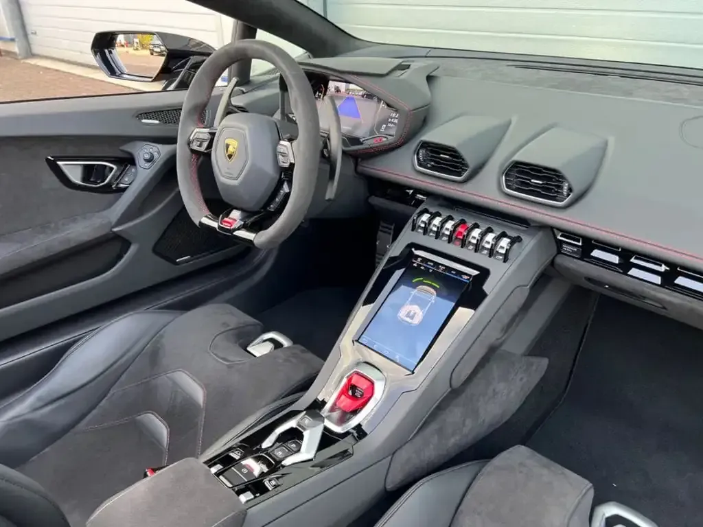 Vista interior de un automóvil deportivo Lamborghini gris, incluido el tablero, el volante y los asientos.