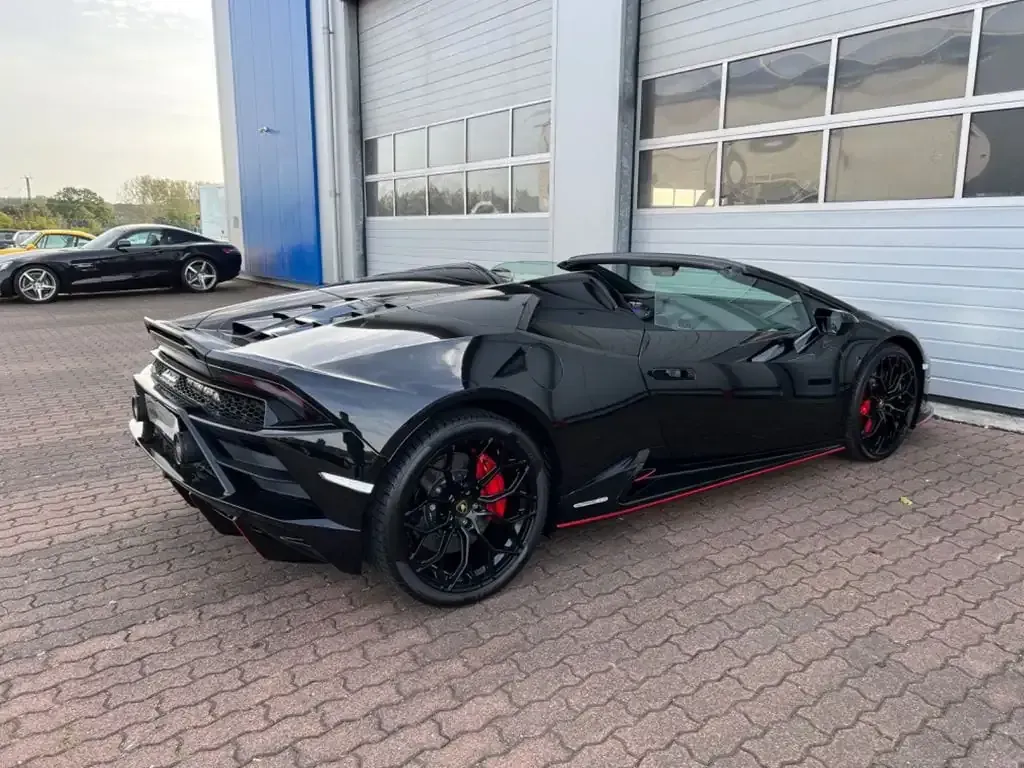 Lamborghini Huracan Spyder negro estacionado afuera de un garaje, con pinzas de freno rojas.