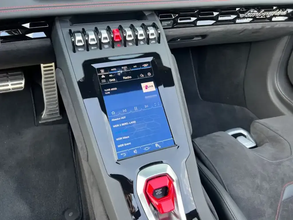 Interior de un Lamborghini, mostrando la consola central con pantalla de infoentretenimiento.
