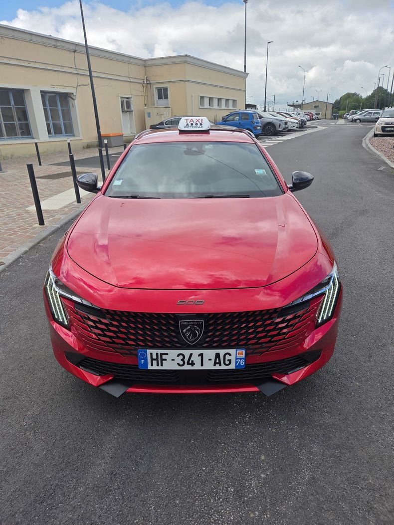 Voiture rouge garée près d'une gare.