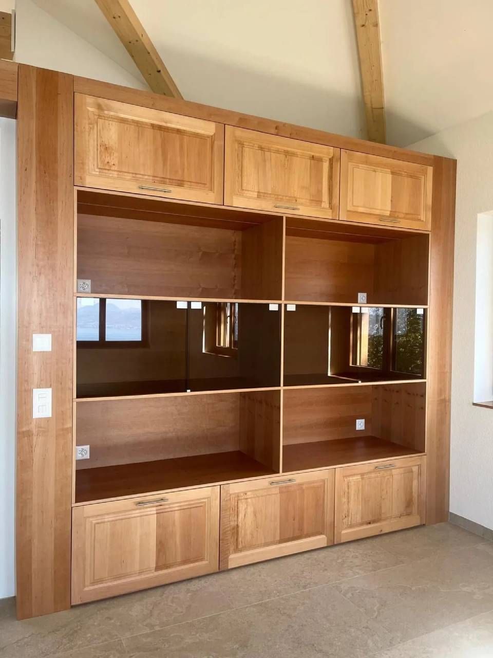 Armoire murale encastrée en bois avec étagères centrales en verre dans une pièce recouverte de moquette