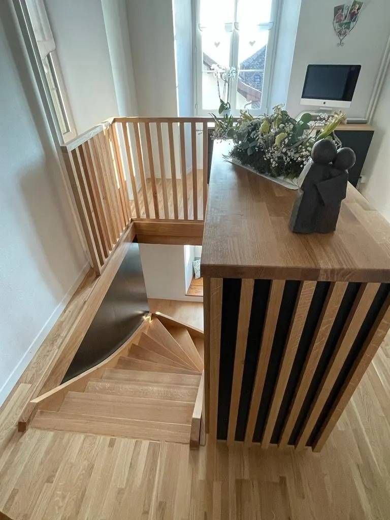 Escalier à côté d'une table à manger en bois et d'une chaise blanche dans un intérieur moderne et lumineux