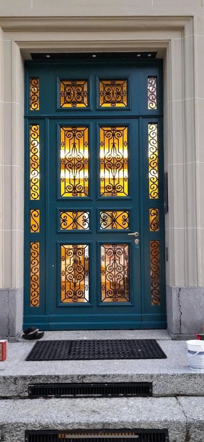 Porte d'entrée ornée bleu-vert avec panneaux de verre ambré en haut d'un escalier en pierre