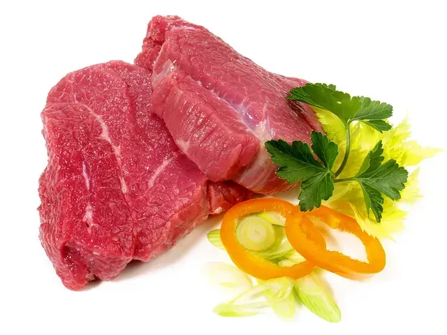 Dos piezas de carne cruda rodeadas de lechuga y pimientos.