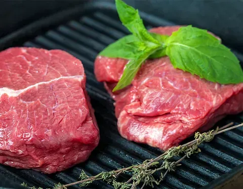 Dos trozos de carne cruda están sobre una parrilla.