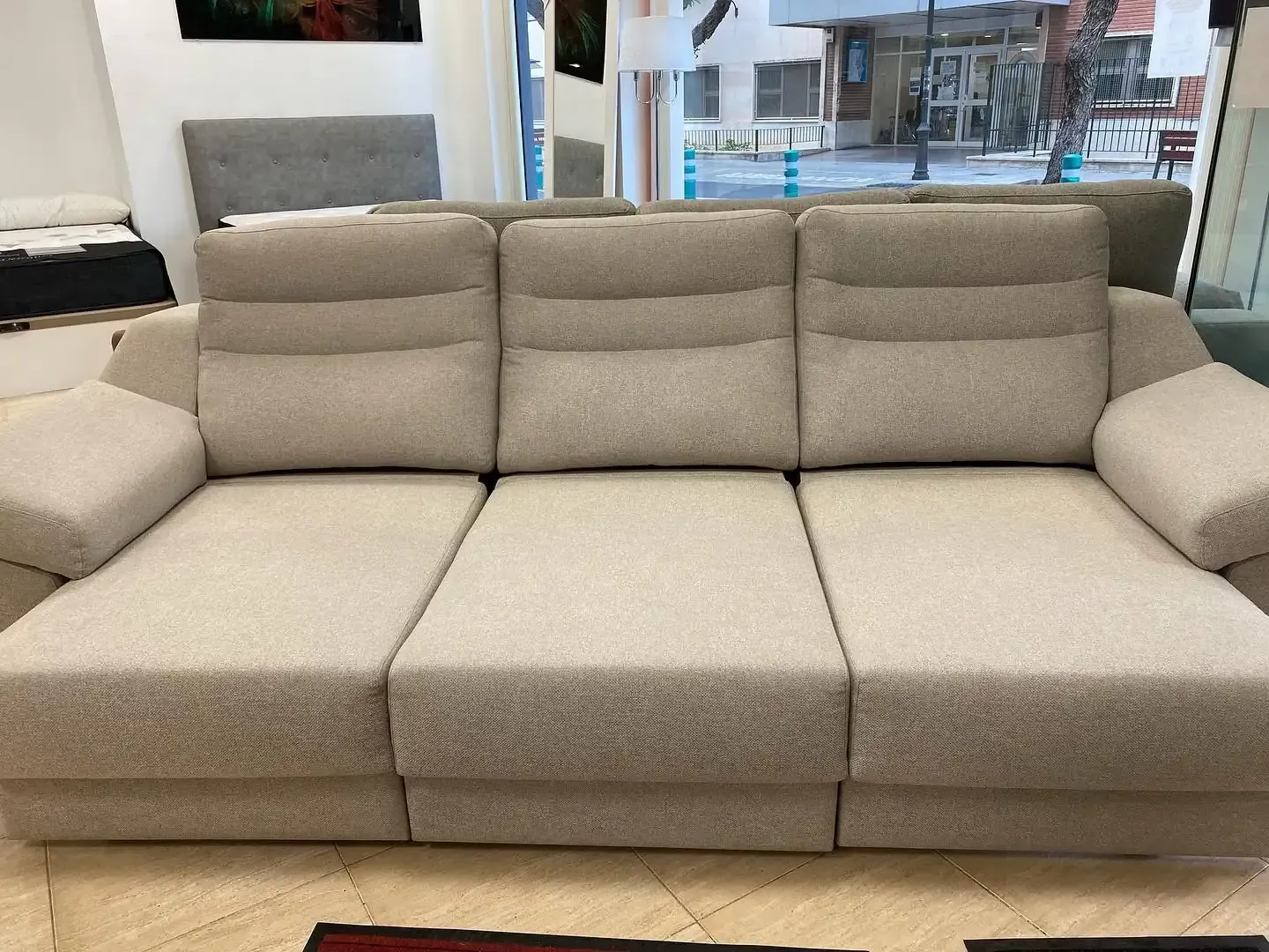 Sofá tapizado en color beige en exposición.